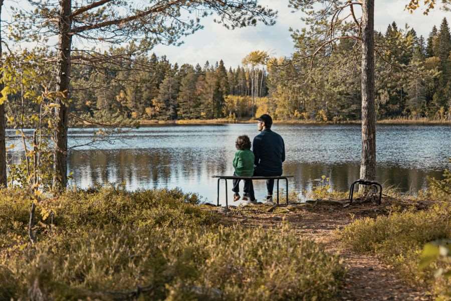 Barn och man som sitter vid en sjö