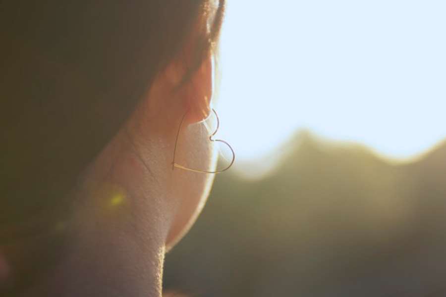 Kvinna sedd snett bakifrån, i motljus. Har ett hjärtformat örhänge i ena örat.