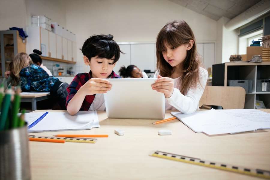 Två elever i klassrum som tittar tillsammans på en surfplatta