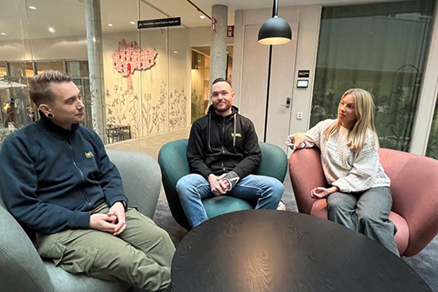 Två personer pratar med varandra och en tredje tittar in i kameran