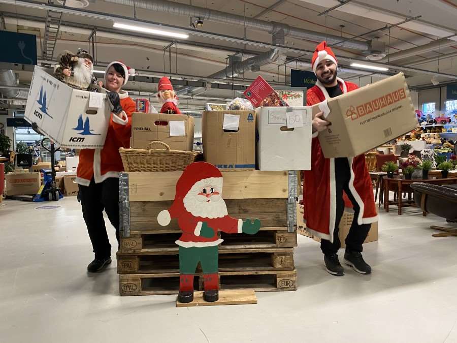 Kvinna och man står iklädda tomtekläder bredvid lådor med julsaker