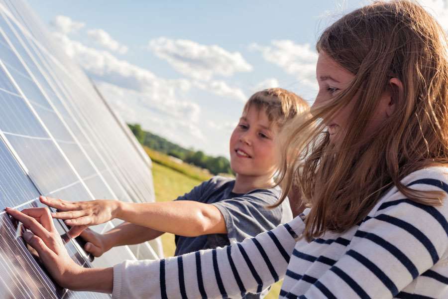 Två glada barn tittar på solceller