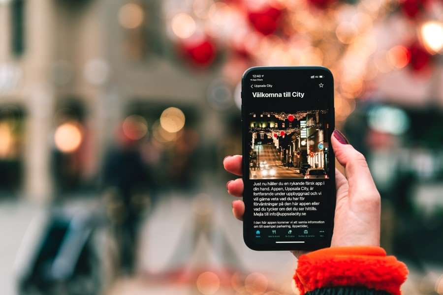 Hand som håller i telefon med cityappen på skärmen