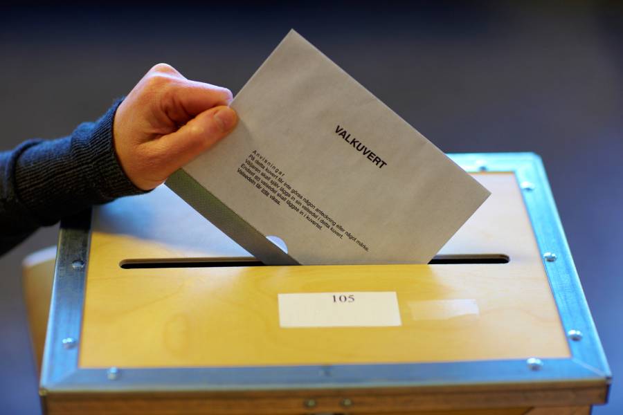 Hand stoppar ner ett valkuvert i valurna