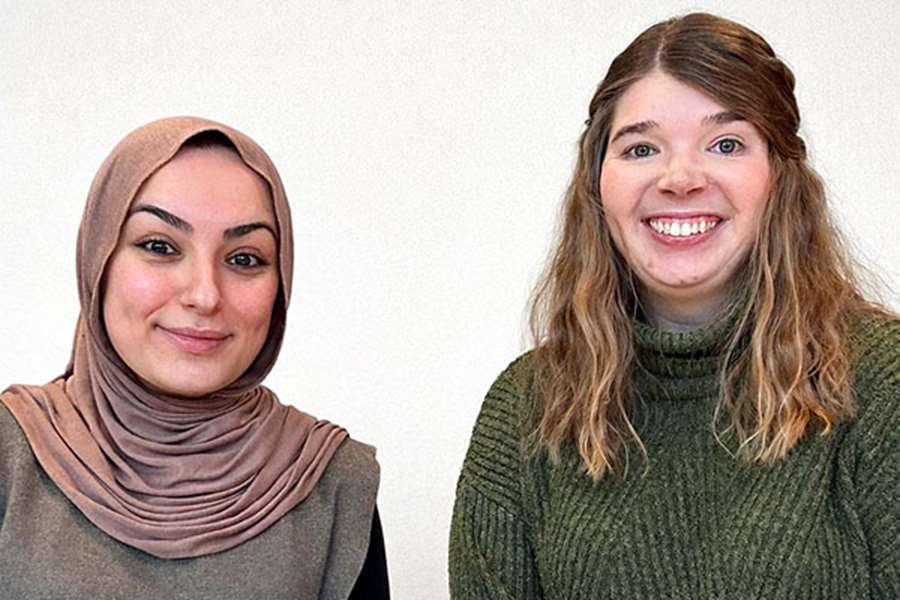 Två kvinnor ler och tittar in i en kamera