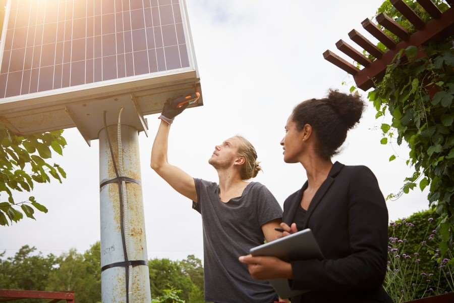 Två personer som står vid en solcellsanläggning