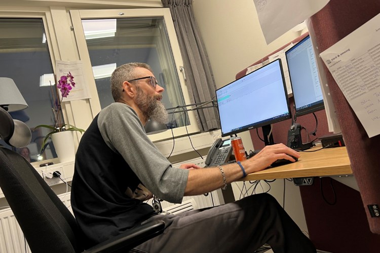 En man sitter på ett kontor framför en dator