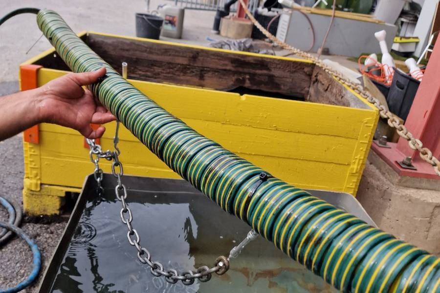 En närbild på hur den perforerade slangen hålls på botten med hjälp av en kedja