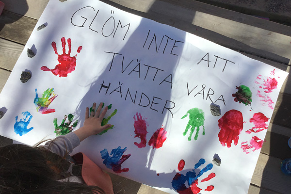Förskolebarn målar med fingerfärg en skylt om handtvätt