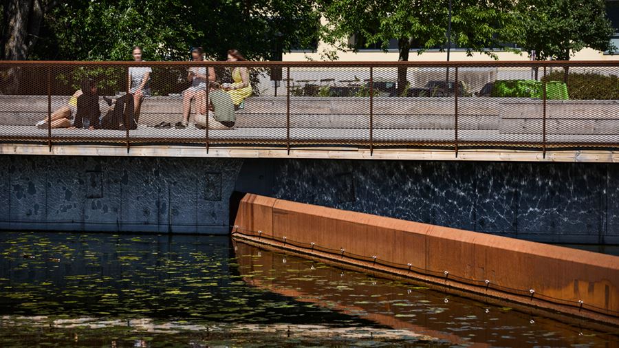 Ungdomar sitter på sittbänkarna på bryggan runt dagvattendammen.