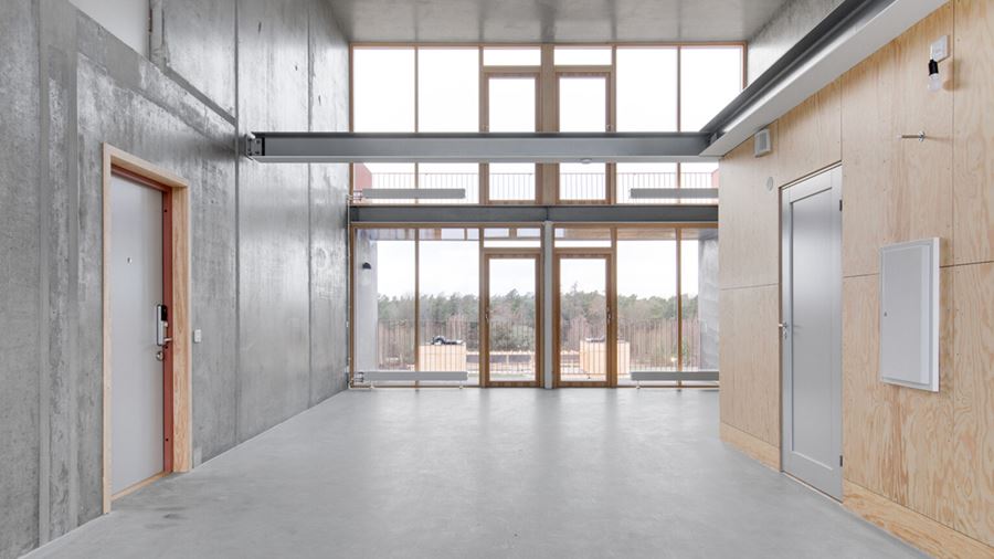 Flerbostadshuset Raw med betonggjutna golv och väggar med inslag av träpaneler och stora fönsterpartier i trä.