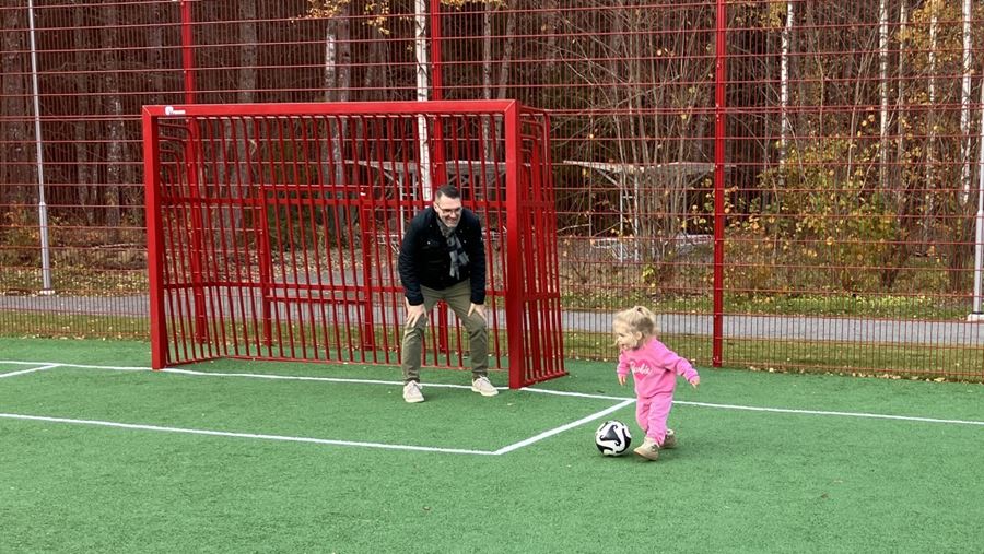 Barn och vuxen spelar fotboll.