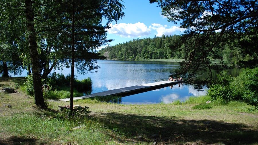 Några personer sitter på bryggan vid Fjällnora naturistbad.