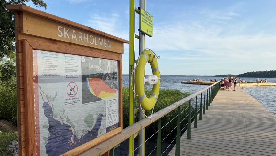 En informationsskylt och en livboj vid bryggan vid Skarholmen