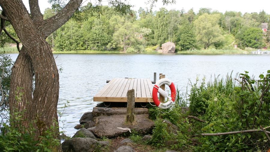 En brygga med en livboj på i Vårdsätrabadet.