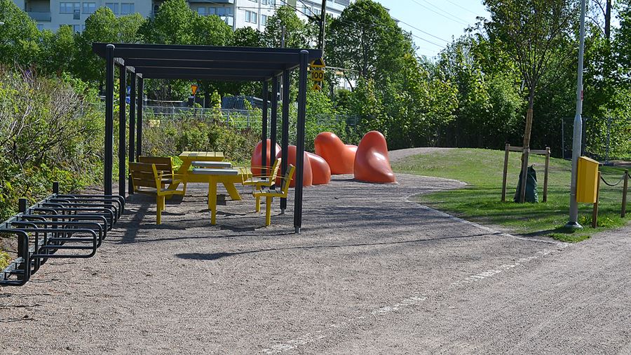 I parken finns en pergola med bord, schackbord och sittplatser under. Här finns även cykelställ och orangea, runda ljusskulpturer.