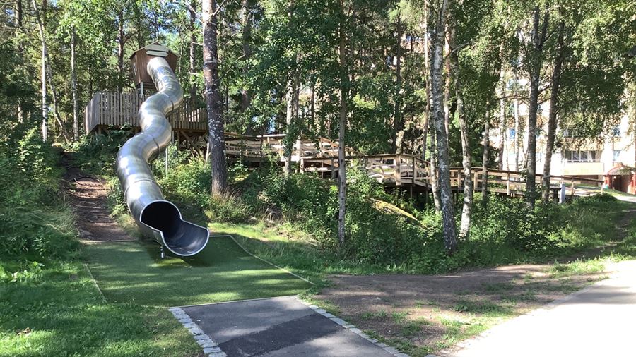 Rutschkana i form av ett slingande stort rör från skogsbrynet.