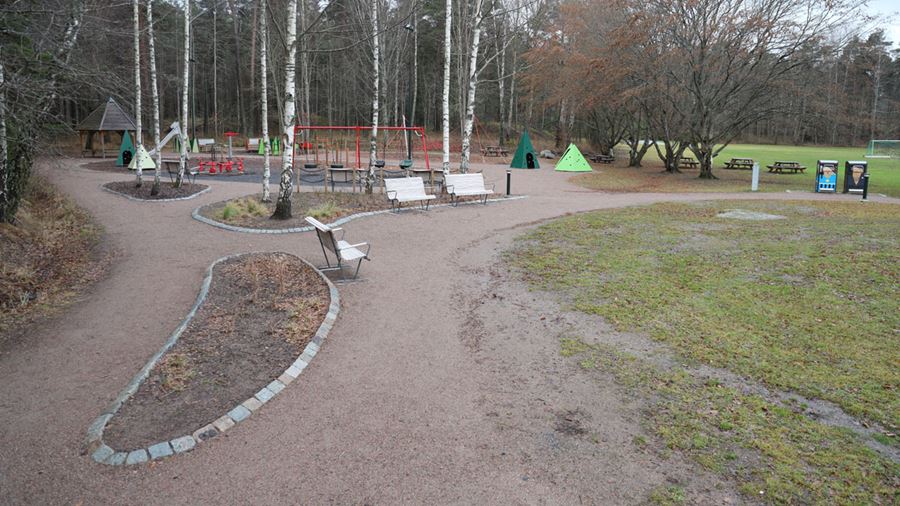 På lite håll syns Norbyvretens lekplats med sittplatser, en röd gungställning och gröna, trekantiga hyddor att gå in i.