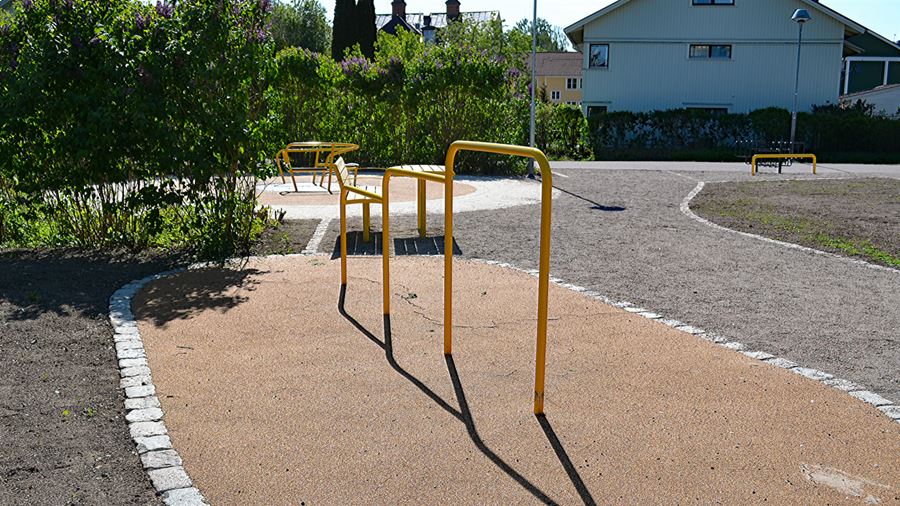 Klargult volträcke och gula sittplats med bord i Spårvägsparken.