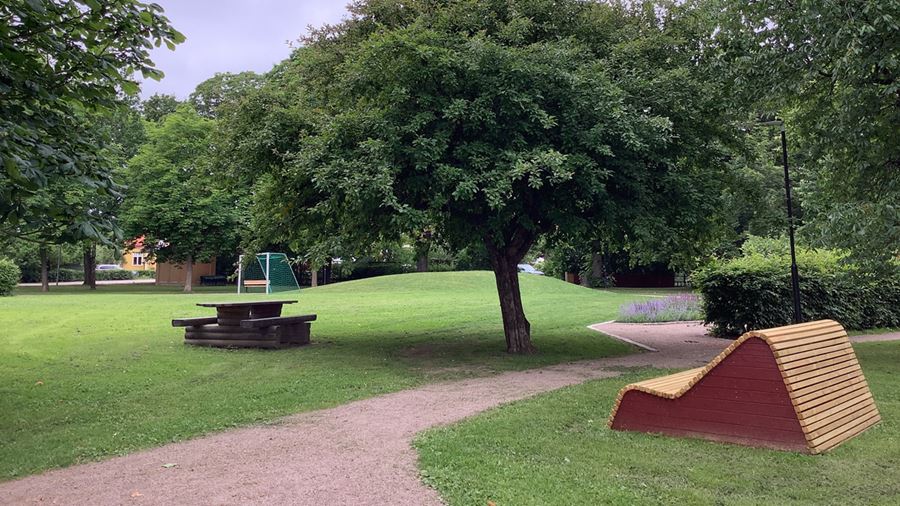 Vilomöbel i trä och sittplatser med bord i parken.