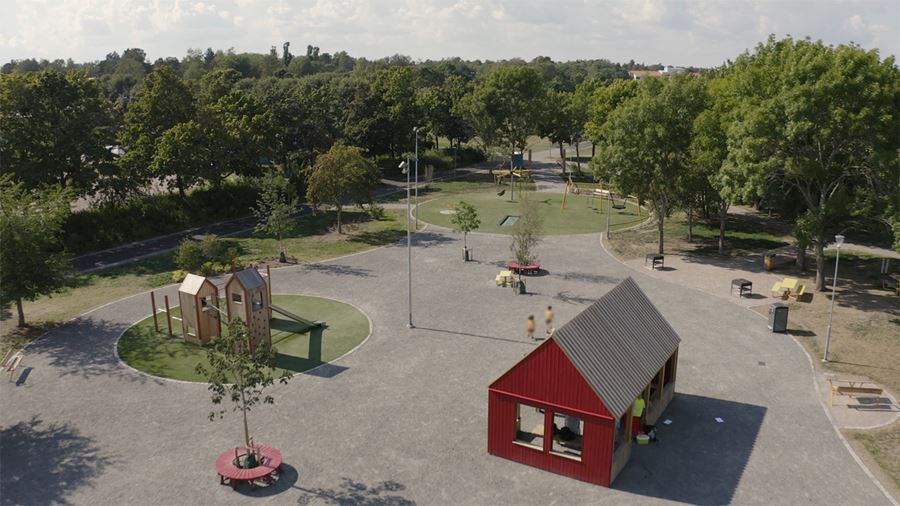 Valsätraparken, vy uppifrån där man ser vindskyddet, klätterställining med rutchkana och grönskan runtomkring.
