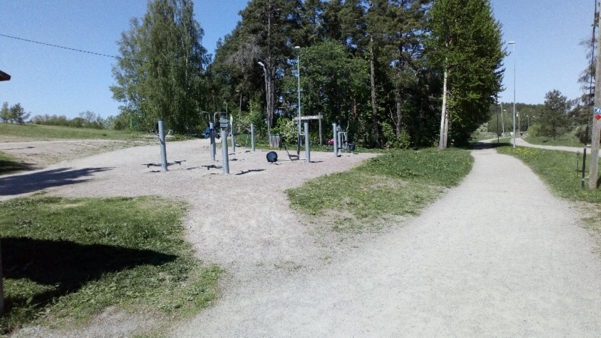Ett utomhusgym på en grusplan och med skog bakom.
