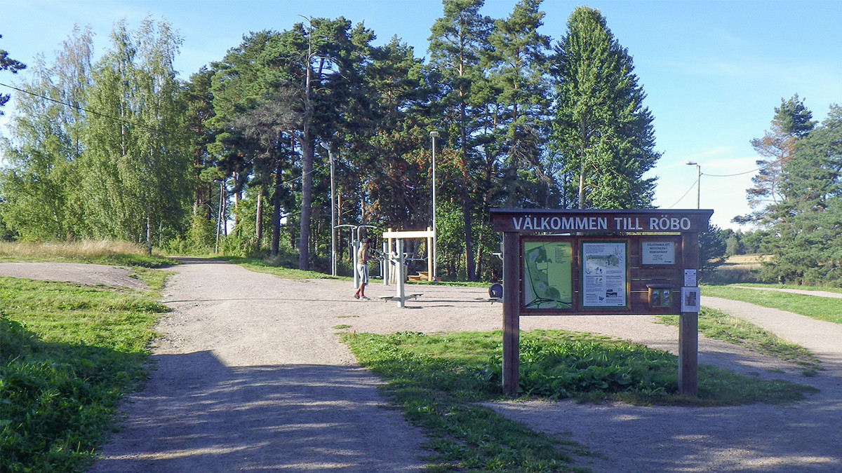 Ett utomhusgym på en grusplan och med skog bakom.