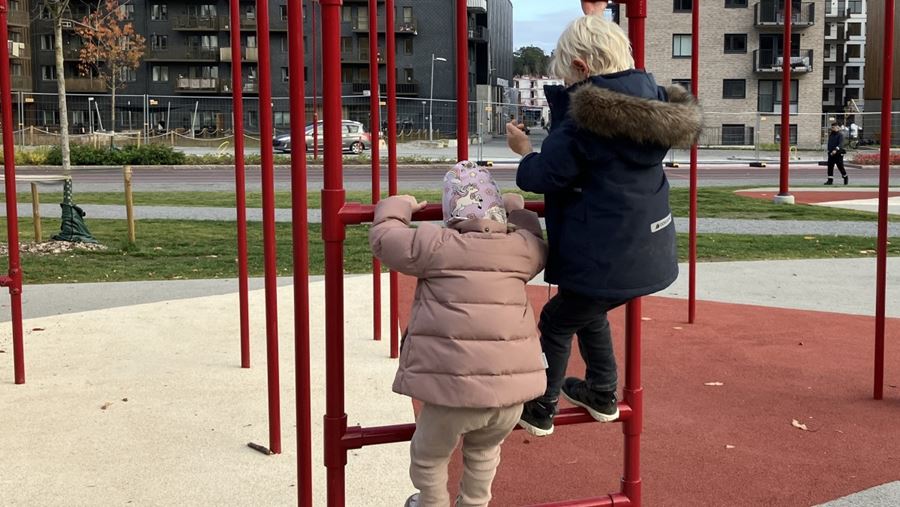 Två barn klättrar i en klätterställning.