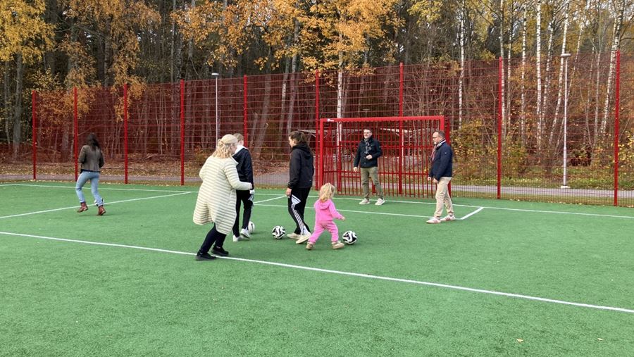 Barn och vuxna spelar fotboll.
