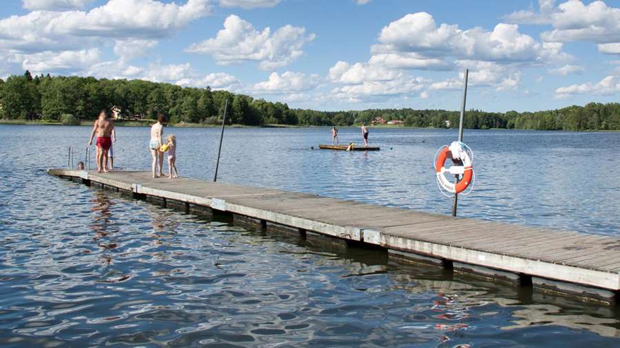 Ett tiotal personer badar från bryggor vid Borgardalsbadet.