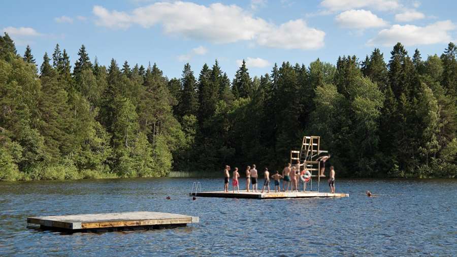 Ett femtontal personer badar från hopptornet på flytbryggan vid Fjällnorabadet.