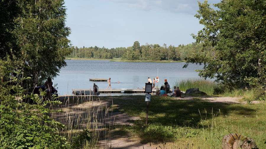 Ett tiotal personer badar vid bryggan i Måviksbadet.