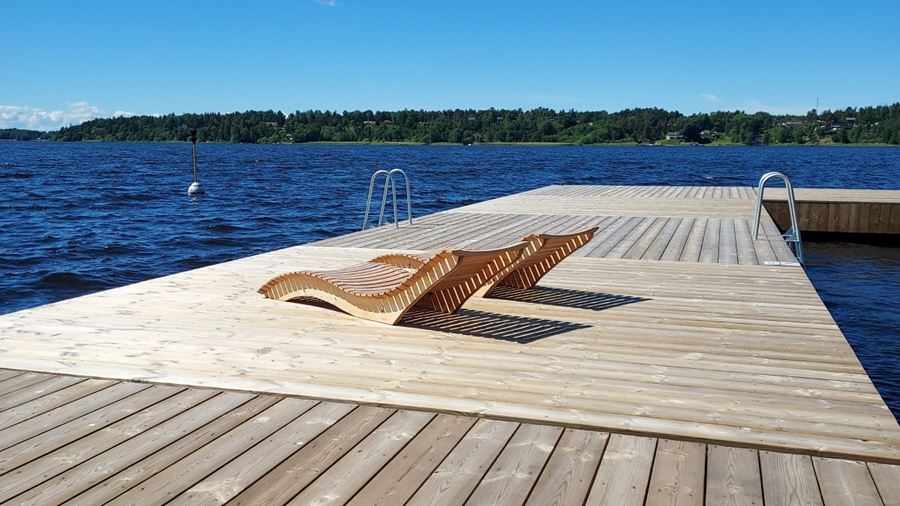 Närbild på bryggan vid Skarholmen och inbyggda solstolar i trä