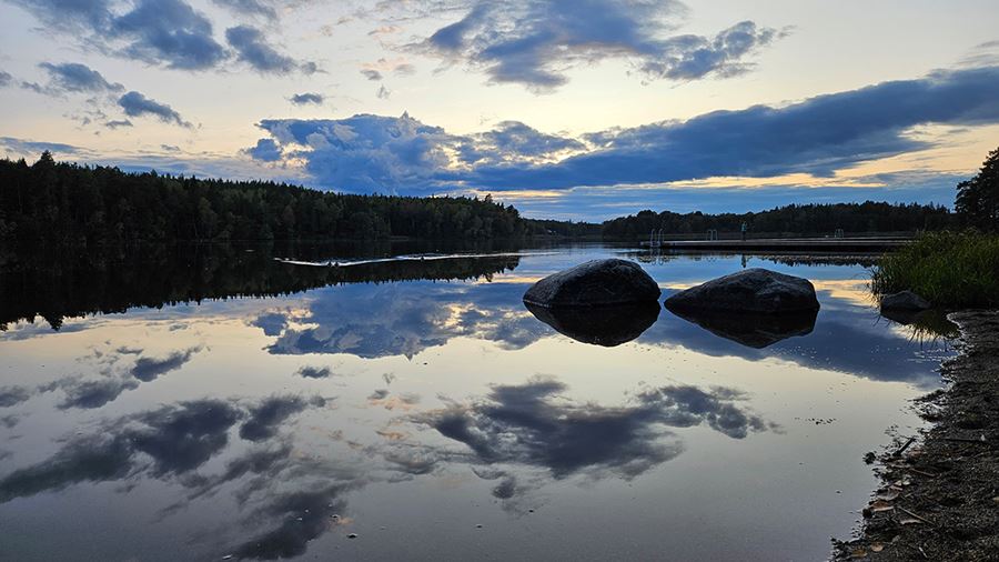 Moln på kvällshimmel speglar sig i sjön i Fjällnora friluftsområde