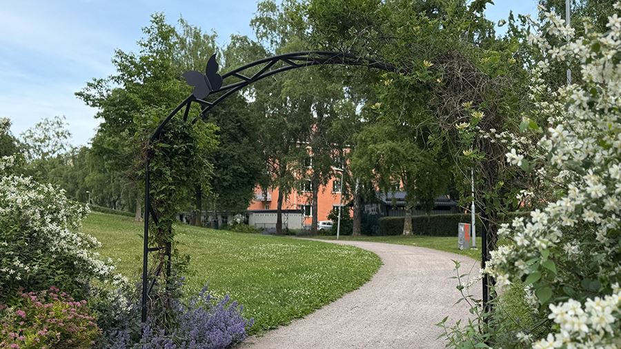 Gångväg under portal med blommor