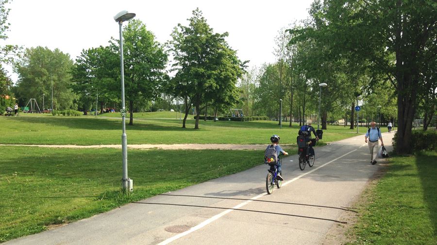 Ett barn och en vuxen cyklar p&#229; en cykelbana i Gr&#228;nbyparken.