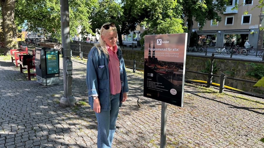 En person i jeans läser på en informationsskylt om Xrundan