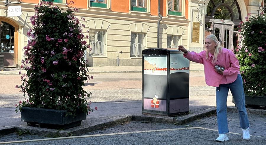 Person i jeans och rosa jacka spelar boule.