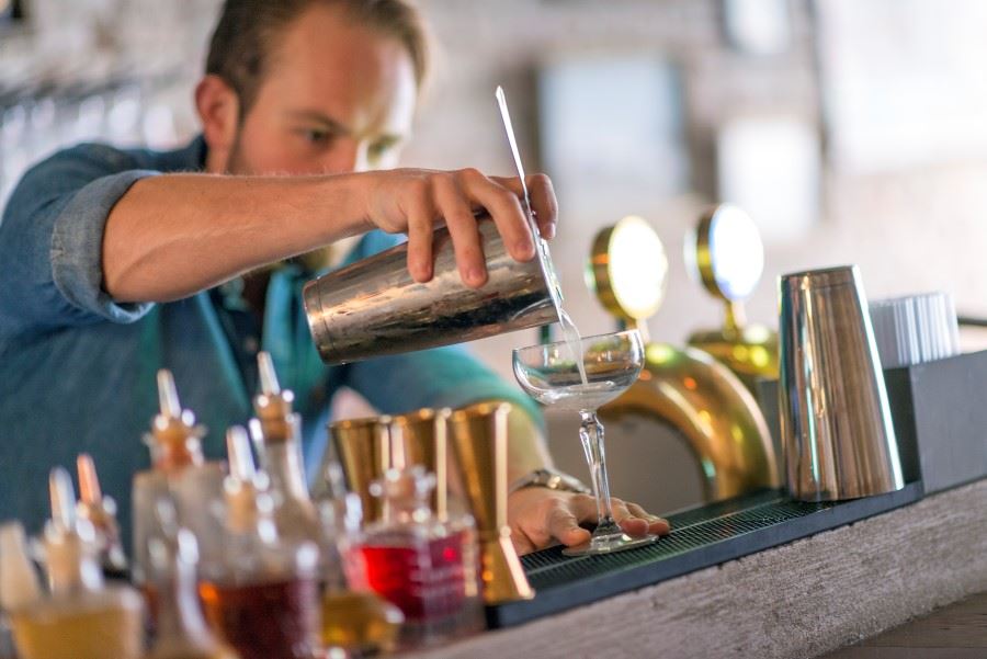 bartender häller upp alkohol vid bardisk