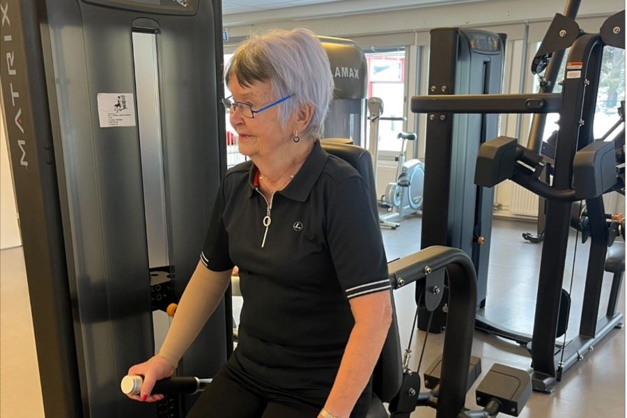 Kvinna tränar styrka på en maskin i ett gym.