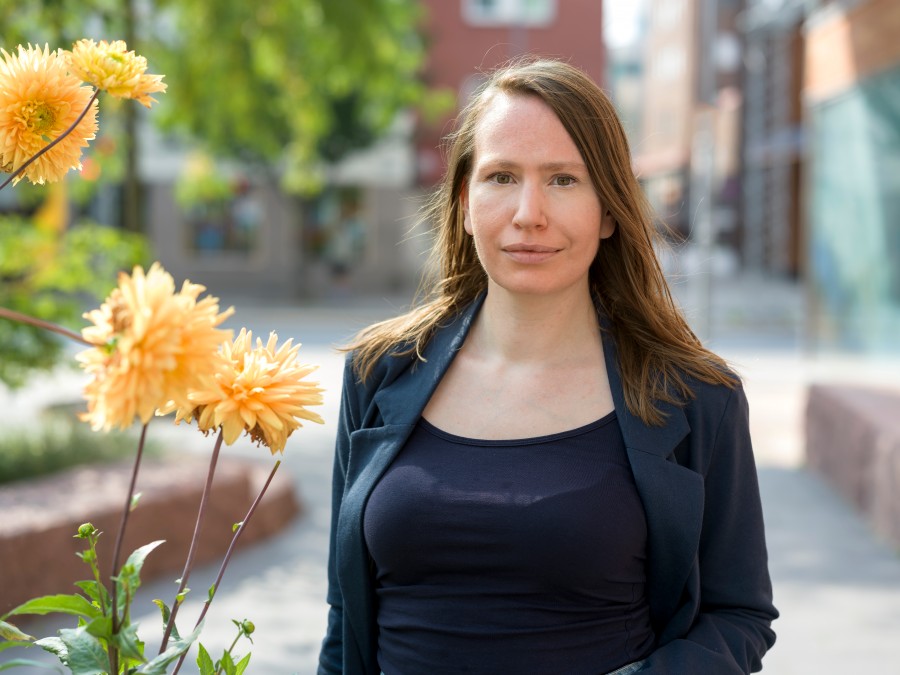 En kvinna står utomhus i vårvärmen och håret blåser lite