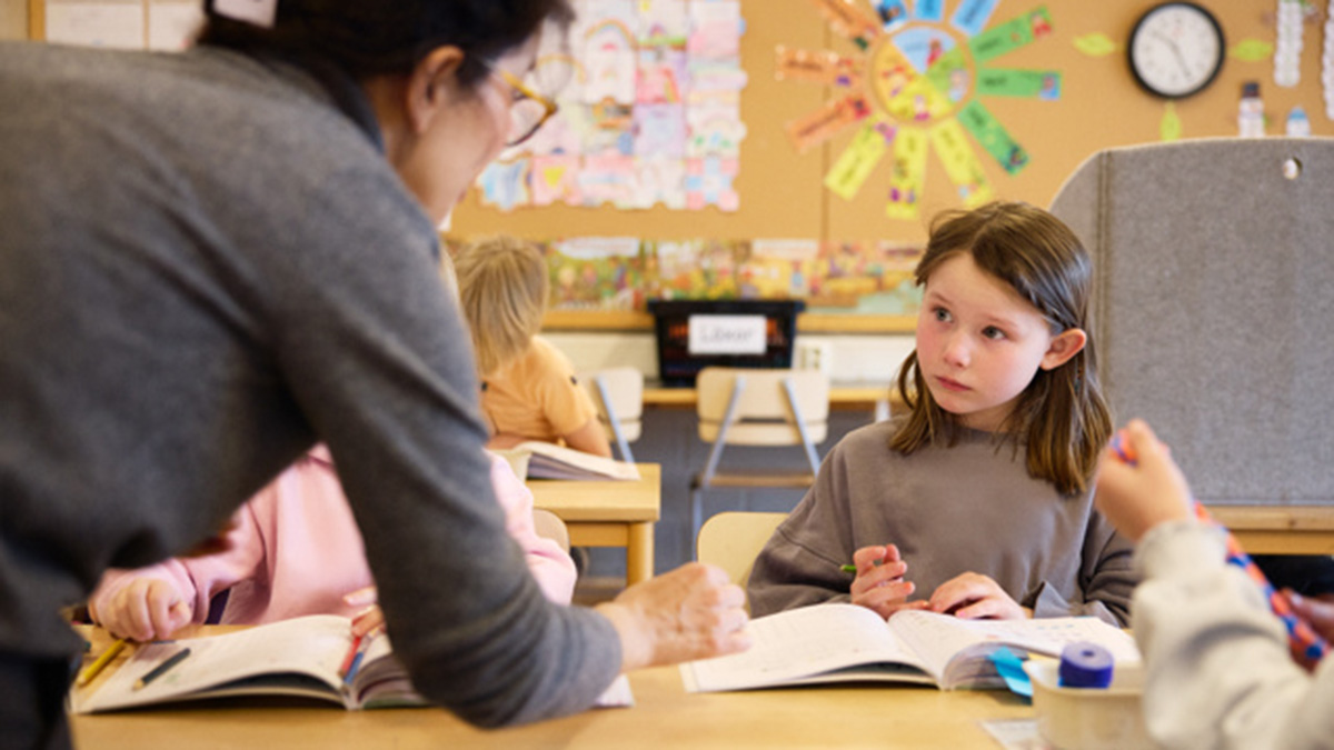 Lärare hjälper elev i förskola vid bänken