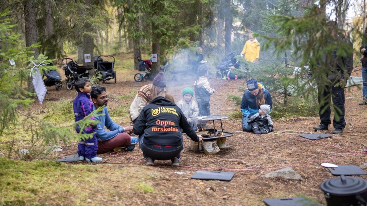 Barn och vuxna och personal i skogen och grillar