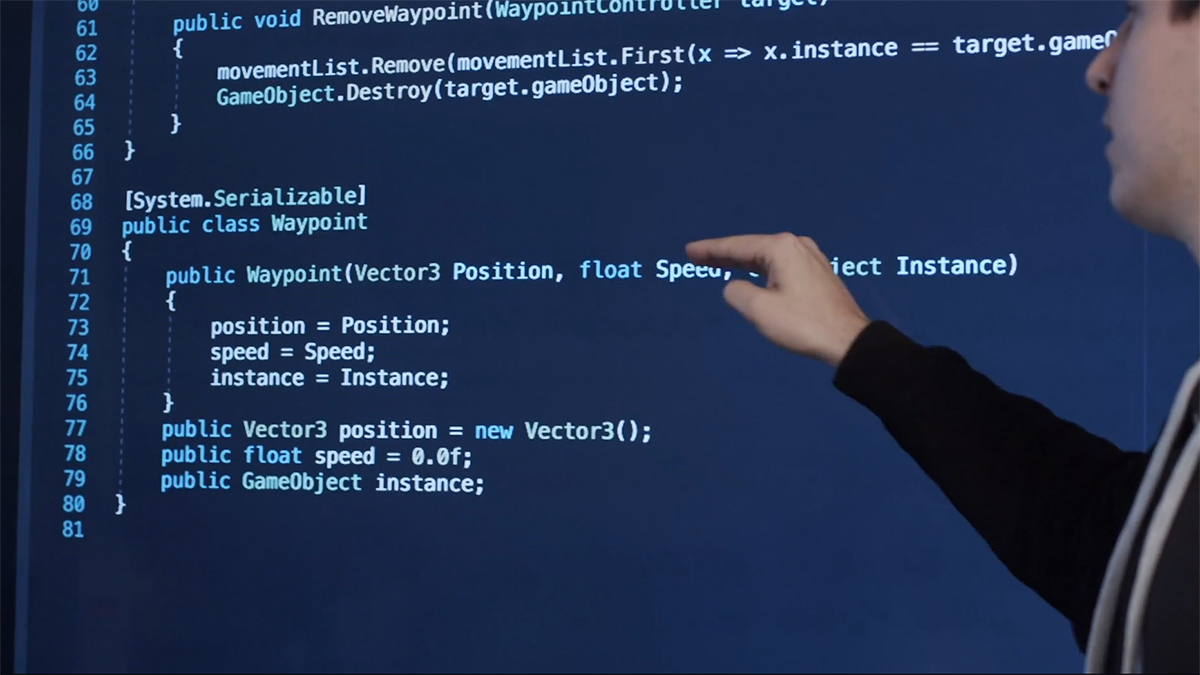 Lärare som pekar på en storskärm där programmeringskoder visas