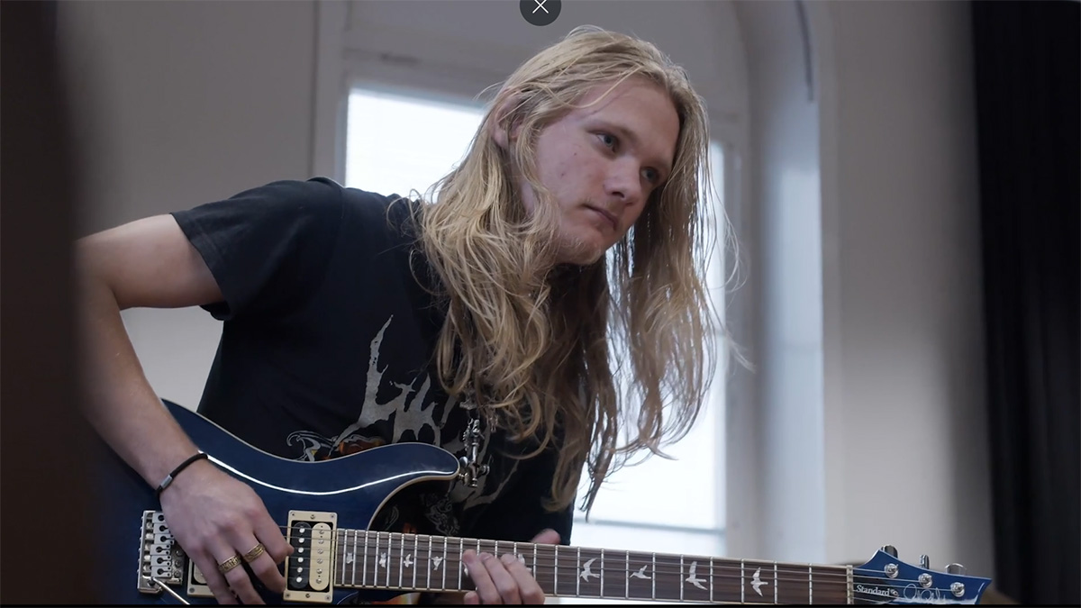 ung långhårig kille spelar gitarr