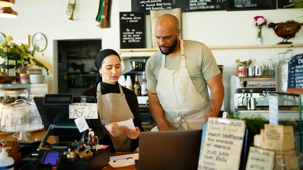 Två personer står funderande vid en disk i ett kafé