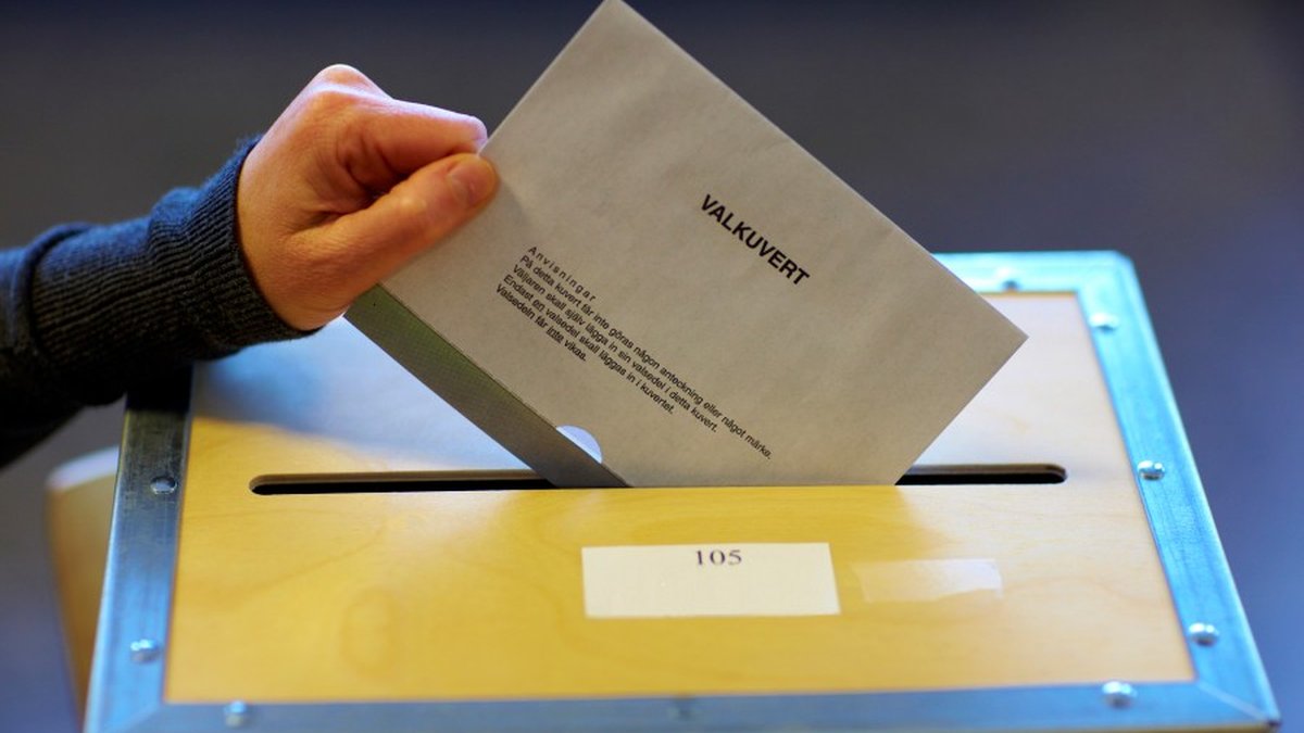En hand stoppar ett valkuvert i en vallåda