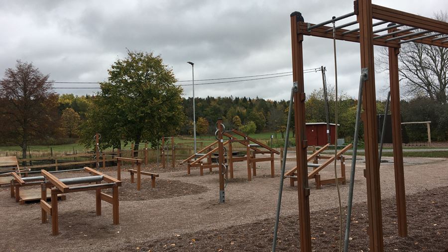 Utegymmet i Hammarskog med olika träningsredskap i trä som står på en grusplan.